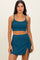 woman wearing a teal ribbed crop top and matching ruched skirt