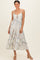 woman wearing a floral print white maxi dress with spaghetti straps and a front tie detail
