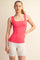 woman wearing a fitted coral square neck tank top with a slim silhouette and white athletic shorts