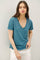 woman wearing a teal v-neck short sleeve t-shirt paired with white linen pants