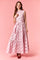 woman wearing a pink sleeveless maxi dress with brown polka dots and a tie waist detail against a pink background