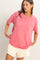 woman wearing a pink short sleeve t-shirt and light beige shorts, posing with hands on hips