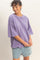 woman wearing a relaxed fit purple oversized t-shirt and light blue denim shorts