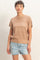 woman wearing a beige knitted short sleeve sweater paired with light blue ripped denim shorts