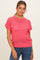woman wearing a bright pink short sleeve knit sweater with a relaxed fit and a wide crew neckline, paired with denim jeans