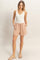 woman wearing a white sleeveless ribbed top and light pink drawstring linen shorts