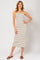 woman wearing a beige and black striped midi dress with spaghetti straps and standing with one hand on her hip