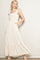 woman wearing a cream floral maxi dress with ruffled straps and pockets, standing against a neutral background