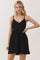 woman wearing a black spaghetti strap mini dress with a fitted bodice and flared skirt