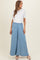 woman wearing a white short sleeve top and light blue wide leg maternity pants