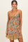 woman wearing a floral print sundress with spaghetti straps and a ruffled hem in shades of orange and blue