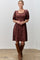woman wearing a burgundy floral print puff sleeve dress paired with knee-high brown leather boots