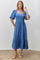 woman wearing a blue midi dress with square neckline and puff sleeves, standing against a white wall