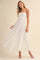 woman wearing a white floral lace maxi dress with spaghetti straps and a fitted bodice