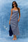 woman wearing a navy and white stripe maxi dress with spaghetti straps and sunglasses, holding a blue tote bag