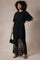 woman wearing a black oversized t-shirt dress layered with a black lace maxi skirt and holding a small handbag
