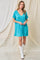 woman wearing a turquoise short sleeve dress with a v-neck and empire waist, paired with white cowboy boots