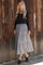 woman wearing a black long sleeve button-up top and a gray tiered midi skirt with polka dots