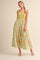 woman wearing a green and pastel patterned tiered maxi dress with a sweetheart neckline and spaghetti straps