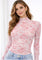 woman wearing a pink floral long sleeve top with a mock neck and a fitted style, paired with high-waisted denim shorts