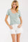 woman wearing a mint green striped short sleeve top with buttons and white denim shorts
