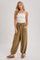 woman wearing a white spaghetti strap top and olive green jogger pants with pockets and drawstring detail