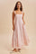 woman wearing a pink floral maxi dress with square neckline and pockets, standing on a neutral background