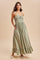 woman wearing a sage green maxi dress with adjustable straps, smocked bodice, and ruffled hem, styled with pockets