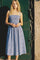 woman wearing a blue and white gingham midi dress with adjustable straps and a smocked bodice