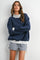 woman wearing a navy oversized sweatshirt with a light grey collar and matching gingham shorts