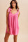 woman wearing a pink sleeveless romper with tie straps and front pockets