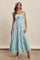 woman wearing a blue and white striped maxi dress with tie straps and a tiered skirt, styled with accessories and sandals