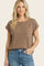 woman wearing a brown short sleeve top with orange trim and a front pocket, paired with blue jeans