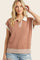 woman wearing a brown short sleeve polo top with a striped hem and collar, styled with distressed denim shorts