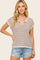 woman wearing a brown and beige striped short sleeve top with a v-neck and denim cut-off shorts