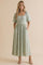 woman wearing a mint green puff sleeve midi dress with floral prints and pockets, styled with strappy heels