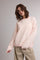 woman wearing a light pink and cream striped oversized sweater with long sleeves and a relaxed fit