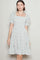 woman wearing a white floral smock dress with puff sleeves and a tiered skirt