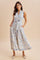 woman wearing a sleeveless blue and white floral maxi dress with a collar, pockets, and a tie waist detail