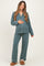 woman wearing a teal maternity pajama set with white piping and a visible baby bump