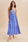 woman wearing a blue maxi dress with a smocked bodice and ruffled hem, standing on a neutral background
