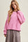 woman wearing a pink oversized knitted sweater with diamond pattern and a gray plaid skirt