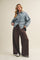 woman wearing a light blue oversized denim shirt and brown wide leg pants with a casual pose