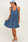 woman wearing a navy and white striped sleeveless swing dress and sandals, smiling while holding the hem of her dress