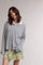 woman wearing a striped oversized long sleeve polo shirt with a white collar and a satin green mini skirt with lace trim