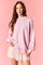 woman wearing a pastel pink oversized sweatshirt paired with a short, sparkly pink skirt