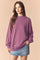 woman wearing a cozy purple oversized sweatshirt paired with a denim mini skirt