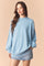woman wearing a light blue oversized sweatshirt with a high neckline and long sleeves, paired with a denim mini skirt
