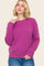 woman wearing a vibrant pink oversized sweater with a round neckline and relaxed fit, paired with blue jeans