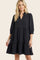 woman wearing a black tiered short sleeve dress with a v-neck and puffed sleeves